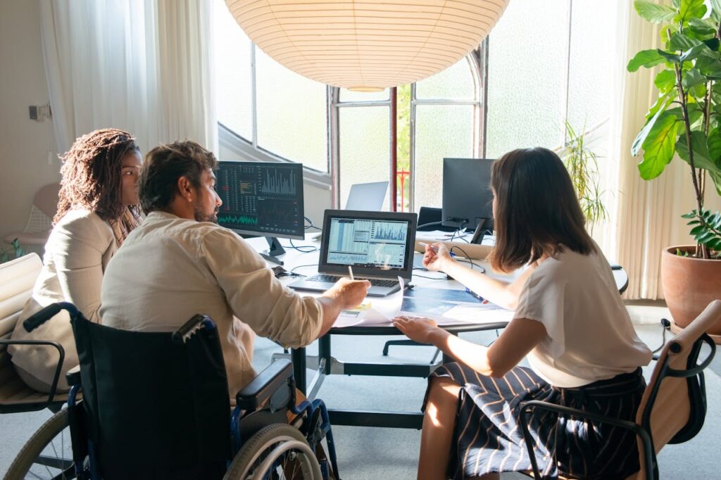 Photograph of Colleagues Talking Near a Laptop with Charts